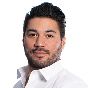 Headshot of Christopher Rodriguez, a Hispanic man with dark hair and facial hair wearing a white button down shirt.