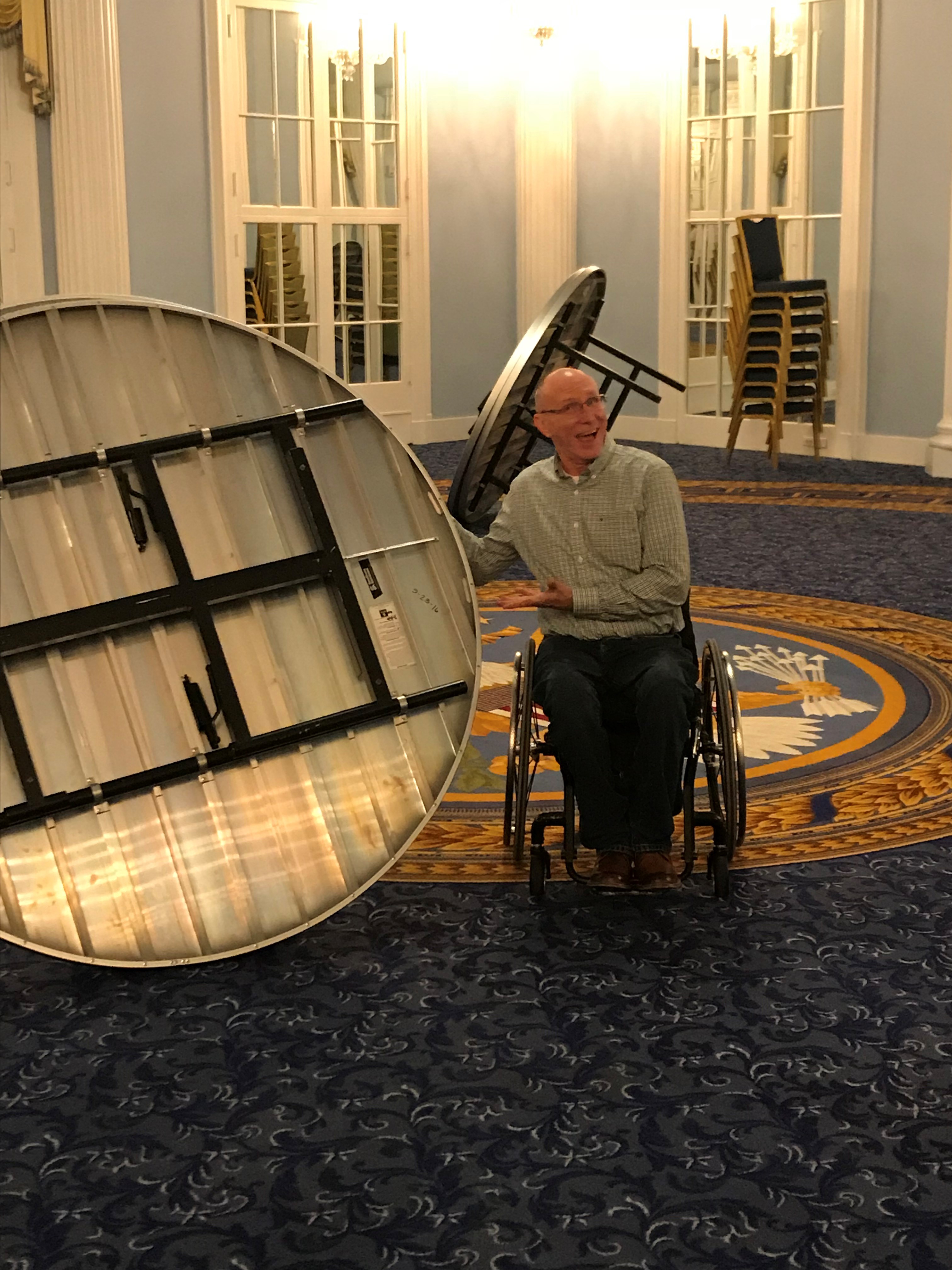 Billy holding table in room decorated like oval office